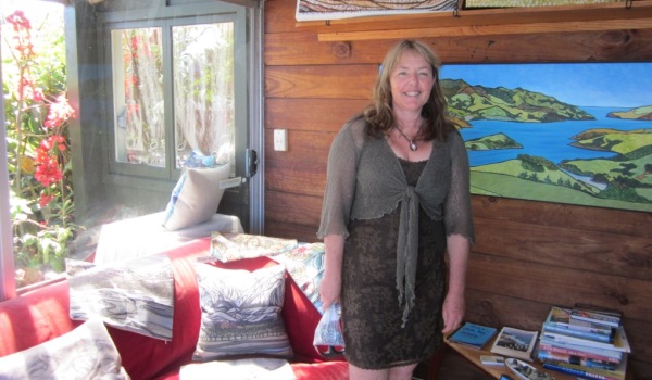 Artist Miranda Caird in her studio with original paitings, prints, cards, cushion covers, outside panels and mobile phone covers.