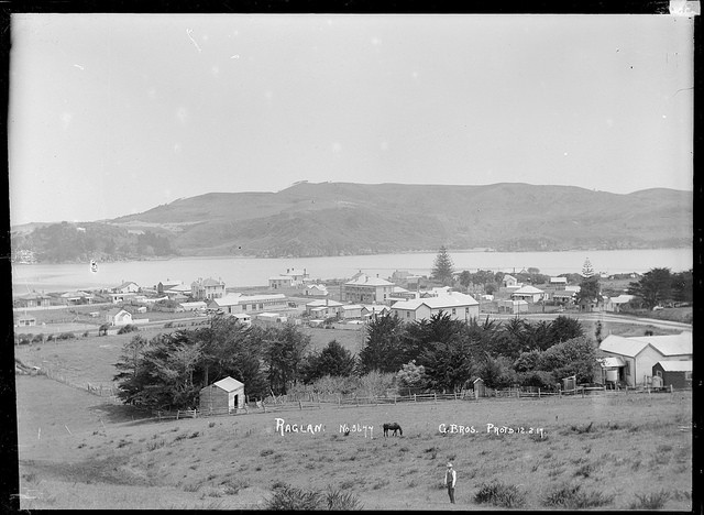 Foreground Gilmour St, old Ben Gilmour's horse and Moon's house. Background 1 Wi Neera St, Anglican church, Farmers store, Post Office, Gilmour Bros Raglan Stores, Royal Hotel, bakery, Langley's store (The Shack), Harbour View Hotel, Moon & Cameron's store, Town Hall, Frank Bray's butchers. Gilmour Brothers (Firm). Raglan, 1917 - Photograph taken by Gilmour Brothers. Price, William Archer, 1866-1948 :Collection of post card negatives. Ref: 1/2-001019-G. Alexander Turnbull Library, Wellington, New Zealand.