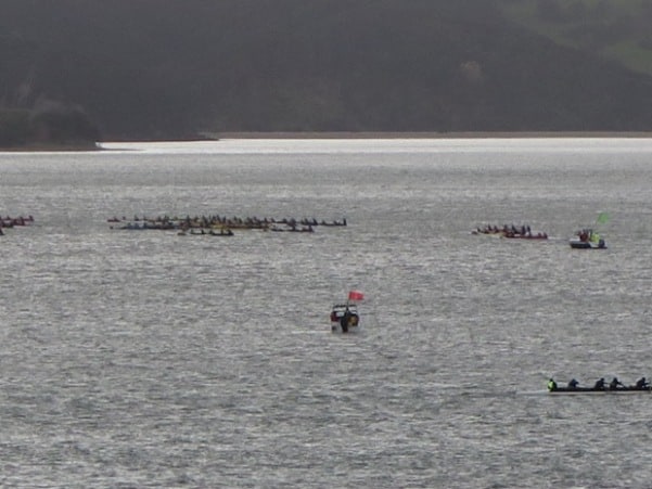 A patrol boat keeps an eye on waka as they turn round the mark off Lorenzen Bay