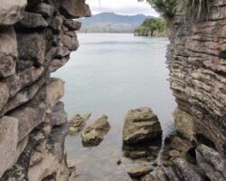 View through two Te Akau limestone stacks across the harbour to Mount Karioi. Image John Lawson 160707teakaulimestoneview