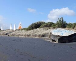 Wainamu Beach near Raglan Domain: Navigation beacons (left) and partly buried concrete pill box gun emplacement (right) built during the Second World War. 161215-pillbox-beach